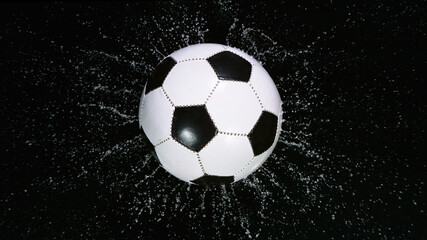 Close-up Foot Falling Soccer Ball into Water. Black background.