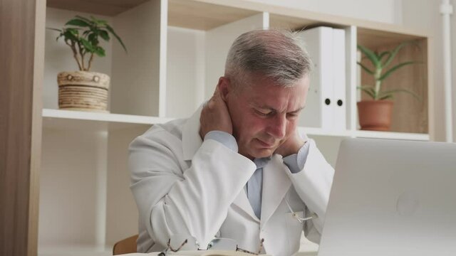 overworked doctor during hard office work, senior man in front of monitor