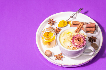 Golden turmeric milk with ice on bright yellow background