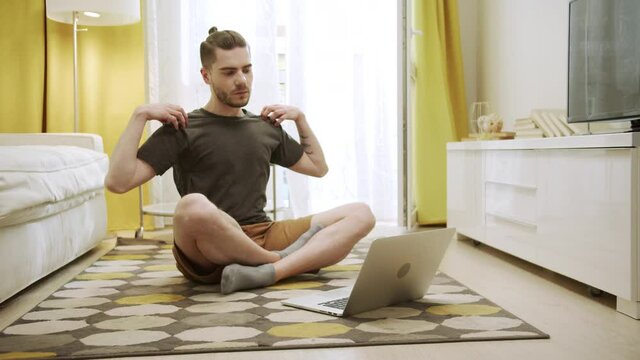 An attractive young man is watching videos and making healthy exercises