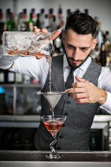 Barman filling glass with cocktail