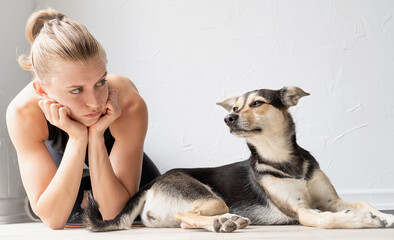 Young sportive woman lying on the floor looking at her dog