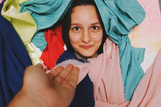 Funny comedy portrait of young woman smiling happy with crazy background of colorful fabrics