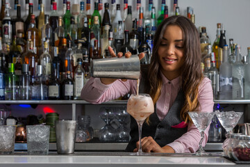 Female barkeeper pouring cocktail into glass
