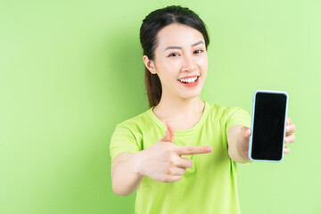 Naklejka premium Young Asian woman using smartphone on green background
