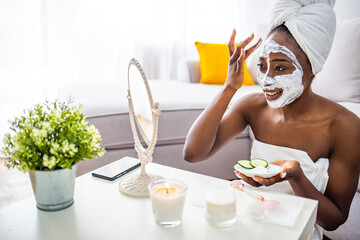 Portrait of a smiling dark-haired woman examining the skin on her face in front of the mirror. Natural homemade facial masks. Beautiful young woman applying avocado facial mask