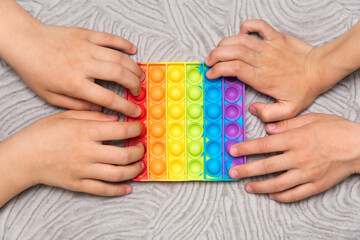 Two kids push sensory popit at the same time on gray background.