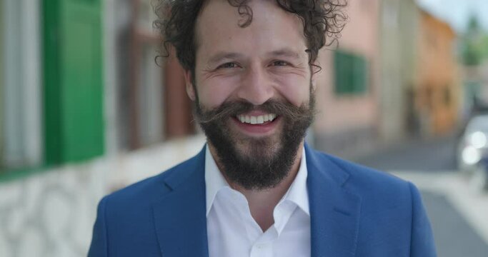 happy smart casual man with curly hair and long moustache wearing smart casual outfit, smiling, looking to side, opening mouth and being shocked outside