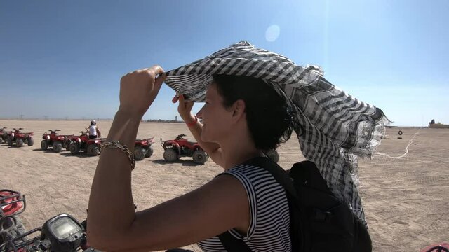 Beautiful woman putting face scarf, rady for driving quad/ATV in the egytian deser