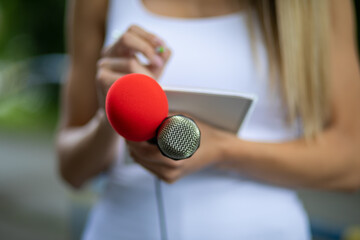 News reporter or TV journalist at press conference, holding microphone and writing notes