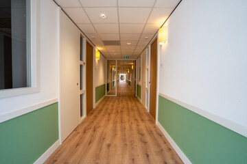 Corridor with doors on both sides. The floor is made of wood and the walls are white