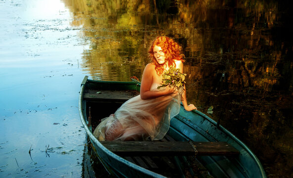 sensual, seductive, young sexy red-haired woman sits in a boat like a siren in an old pre-Raphaelite painting, copy space