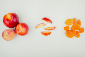 top view of fresh ripe peach and nectarine fruits with nectarine slices and dried apricots on white background