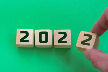 Businessman hand holding wooden cube with flip over block 2021 to 2022 START word on table...