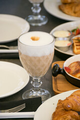 Coffee drink in a beautiful glass in a restaurant on a served dark table among various sweets, vertical format