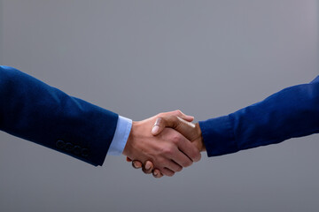 Caucasian and african american business people shaking hands, isolated on grey background