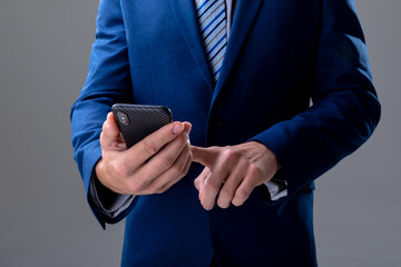 Midsection of caucasian businessman using smartphone, isolated on grey background