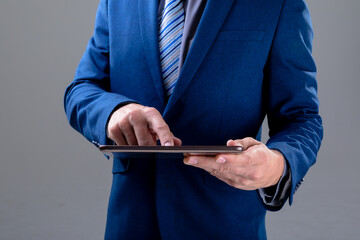 Midsection of caucasian businessman using tablet, isolated on grey background