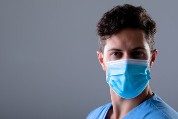 Caucasian male doctor wearing face mask, isolated on grey background