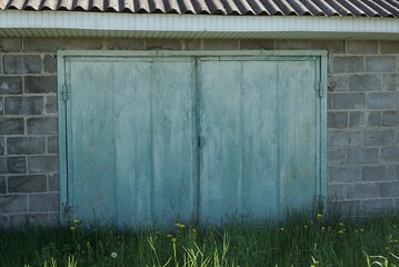 facade of a gray bricks garage with green iron gates on the street