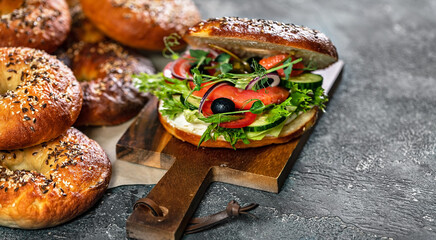Food banner. New York bagel with cream cheese, salad, cucumber, herbs, olives and salted red fish. Homemade tasty sandwich salad. Appetizing and crunchy baked. Excellent breakfast or snack. Copy space