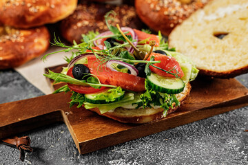 Homemade New York bagel with cream cheese, salad, cucumber, herbs, olives and salted red fish. Tasty sandwich salad. Appetizing and crunchy baked. Excellent breakfast or snack. Cook at home Copy space