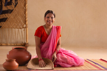 A rural woman grinning with a sieve.