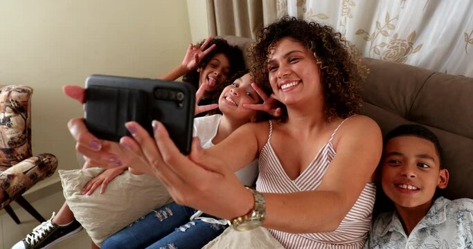 Mother taking selfie with children at home sofa holding phone takes photo