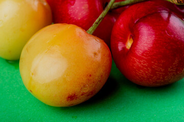 close up view of ripe rainier cherries on green background