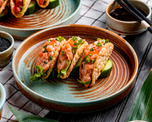 side view of  salmon tacos with red caviar and green onion on a plate on plaid tablecloth