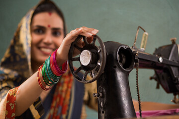 A woman grinning with a sewing machine. - obrazy, fototapety, plakaty