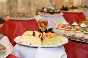 Catering plate with sliced fruit apples, pears, tangerine slices, grapes and a glass of apple juice
