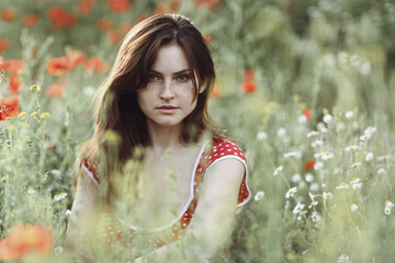 Beautiful girl sitting in the grass and poppies - 442508650
