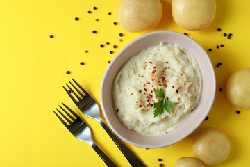 Plate of mashed potatoes and ingredients on yellow background