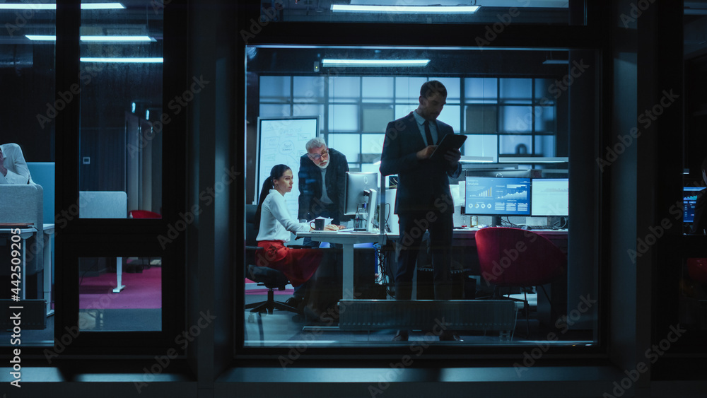 Poster Shot from Outside: Businessman Working on a Digital Tablet Computer in the Office. Manager Checking Emails while Standing by the Window. Employee Planning Financial Tasks and Business Development.
