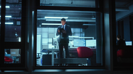 Shot from Outside: Businessman Working on a Digital Tablet Computer in the Office. Manager Checking...