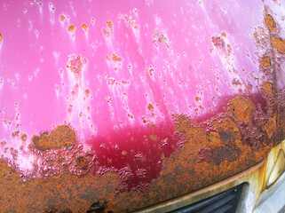 Sheet metal corrosion of bonnet of old red wine-colored car. Rusty messy surface. Damaged grunge dirty texture from road salt. Rust background. Protecting the automobile concept. Paint work. Insurance