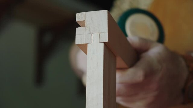 Joiner collects furniture element. Carpenter puts the wood element into the groove.
