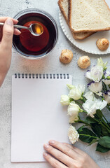 Top view of a blank notepad sheet and woman's hand in breakfast setting