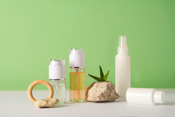 Fototapeta na wymiar A set of cosmetics products with natural materials on a green background. Stones, plant and wooden decorative figures. Natural organic cosmetic. Beauty concept. Wabi sabi trend