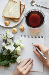 Hands writing on a notepad, breakfast setting