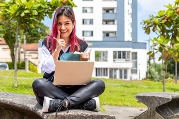 Adult high school student girl pointing up with finger, with laptop and note pad