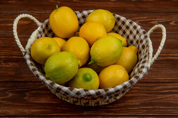 side view of fresh ripe lemons in a white wicker basket on wooden background