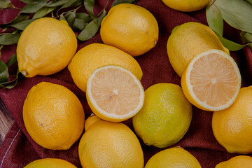 Obraz na płótnie Canvas side view of fresh ripe lemons on dark red fabric background
