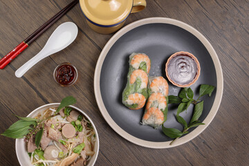 Vietnamese prawn shrimp see through rice paper spring roll poh beef noodles soup beef ball brisket tripe stomach parts thai basil lime rustic wooden table chopsticks spoon sauce dark plate tin mug