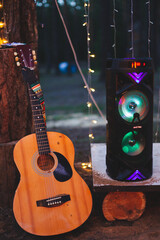 Acoustic wooden guitar musical instrument and music column glowing with different colors composition musical equipment