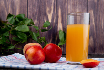 side view of fresh ripe nectarines with a glass of peach juice on rustic background