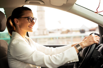Beautiful businesswoman driving a car. Portrait of smiling woman sitting in the car....