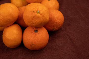 side view of fresh ripe oranges on brown fabric background
