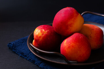 Food concept organic fruit Nectarine in rustic iron tray on black background with copy space